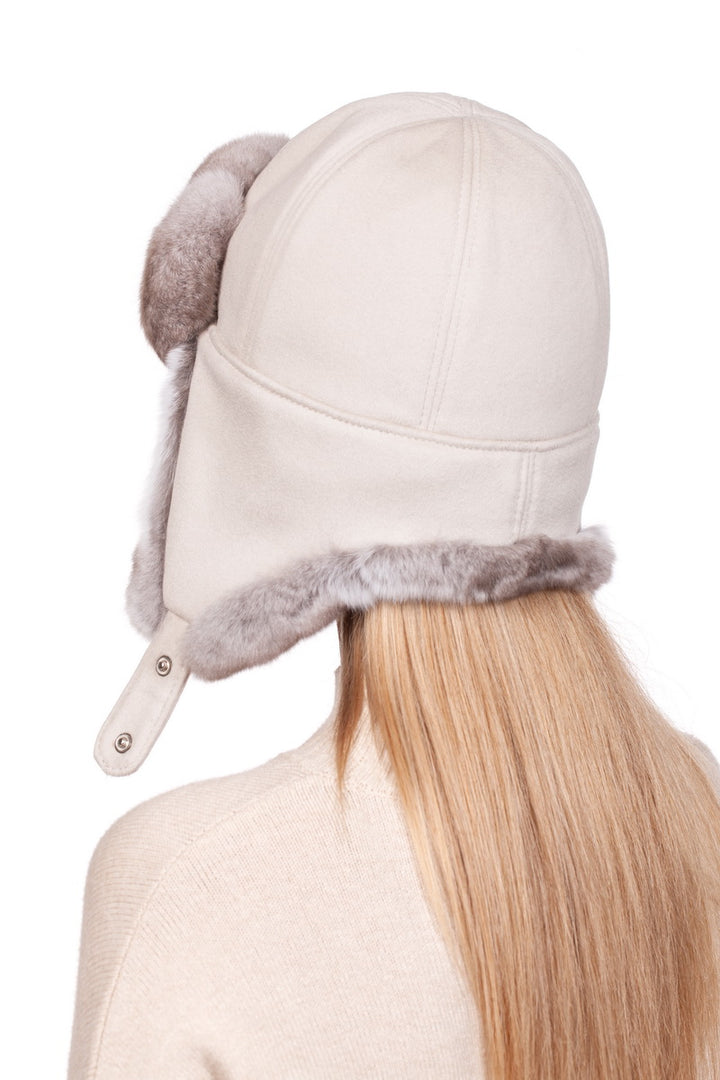 a blond women standing by her back wearing cream beige ushanka earflap hat for winter