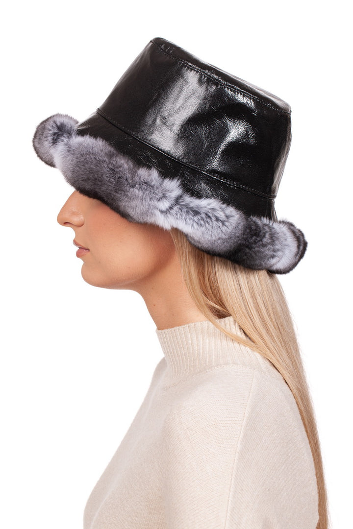 A person with long blonde hair dons the Chinchilla Fur Panama Hat by FurbySD, radiating the sophisticated charm of a luxury accessory. The hat, featuring a gray fur rim reminiscent of chinchilla, is seamlessly styled with a cream sweater set against a pristine white backdrop.