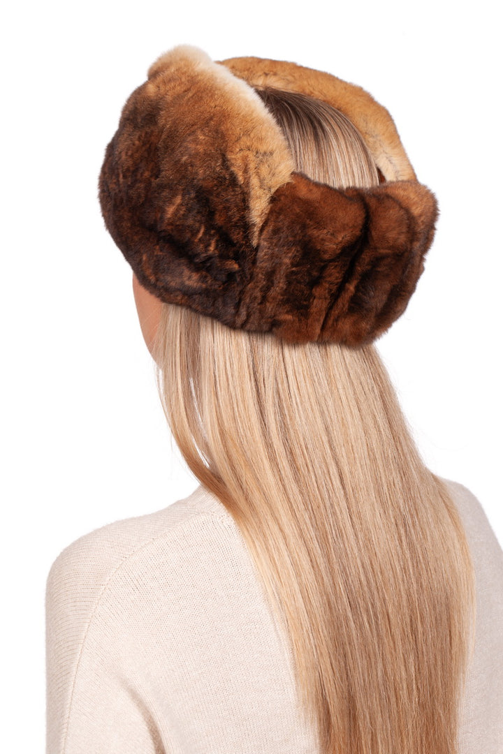 A person with long blonde hair is wearing a large, fluffy Rex Rabbit Fur Headband by FurbySD in brown, enhancing their elegant appearance. They are clad in a cream-colored sweater, radiating cozy sophistication against the plain white background.