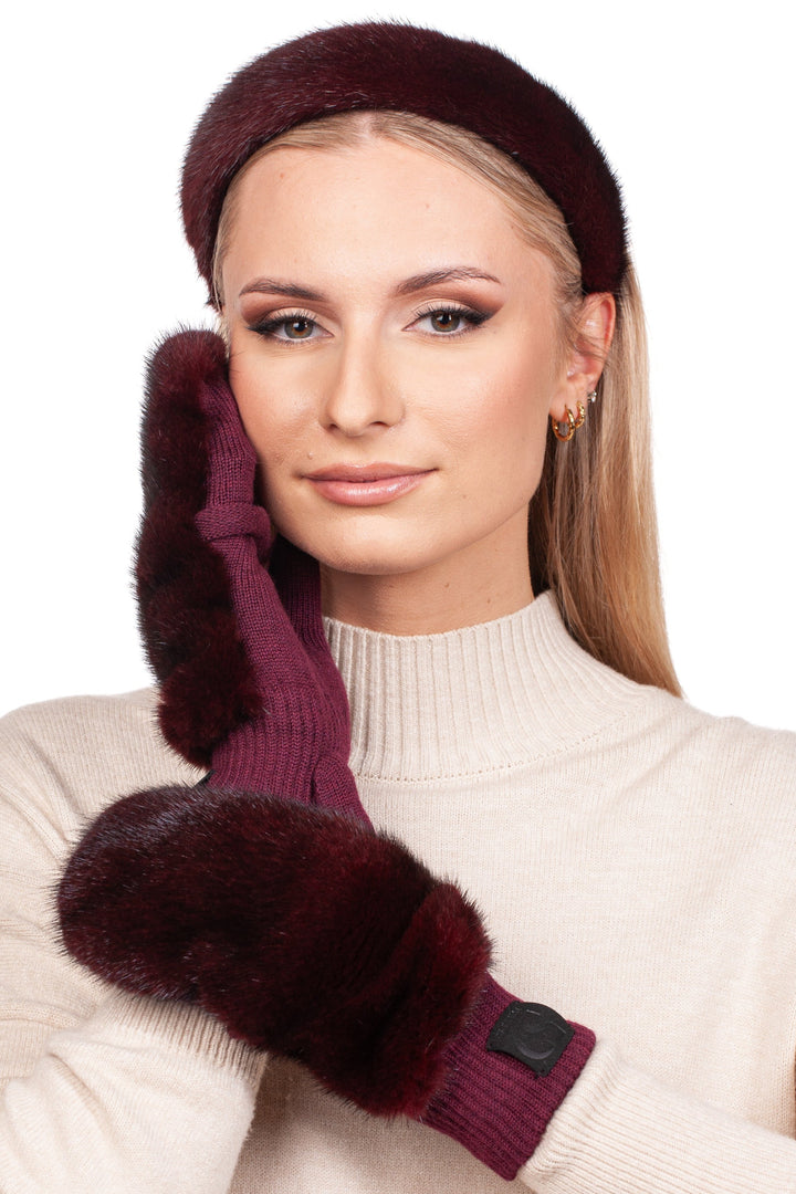 A woman models the Red Mink Fur Mittens and Hairband Set by FurbySD, pairing it with a cream sweater. With one hand touching her face, she exudes sophistication, her straight light blonde hair complementing the luxurious accessories as she gazes forward with a slight smile.