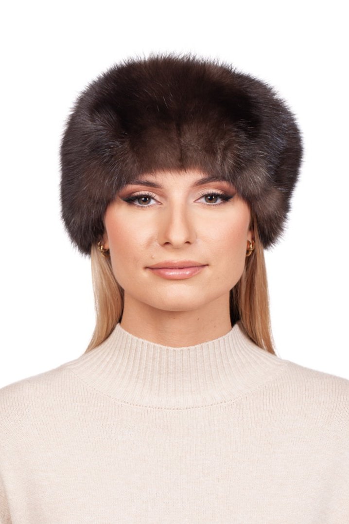 The individual with long hair is sporting a luxurious Russian Sable Fur Headband from FurbySD, paired with a brown fur hat and a beige turtleneck sweater. The simple white background highlights the exquisite headband and their facial features.