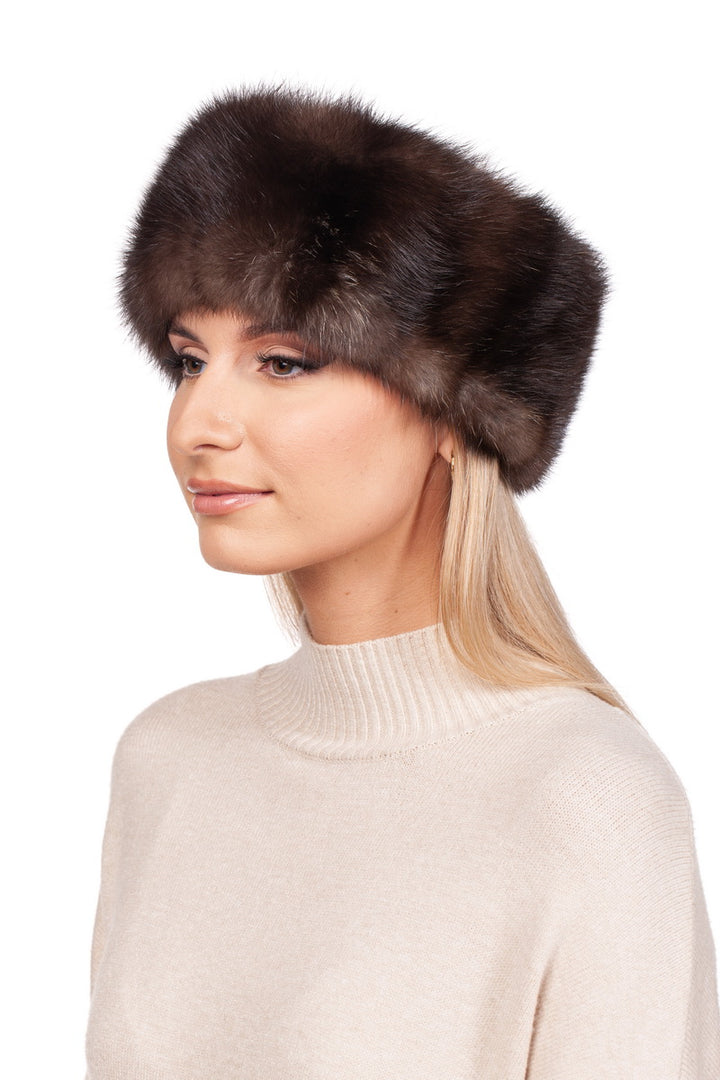 A person with long blonde hair is wearing a brown Russian Sable Fur Headband by FurbySD and a beige turtleneck sweater, handcrafted in Lithuania. They are gazing to the left against a plain white background.