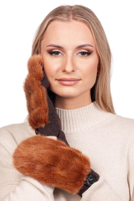 A person adorned in a beige sweater elegantly poses with FurbySD's Rust Brown Mink Fur Mittens, gently pressing one to their cheek against the plain white backdrop.