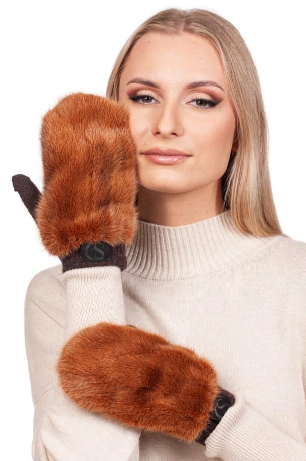 A person adorned in a cream-colored sweater gracefully poses with two exquisite FurbySD Rust Brown Mink Fur Mittens. One mitten softly conceals part of their face, while the other rests elegantly on their arm against the pristine white backdrop.