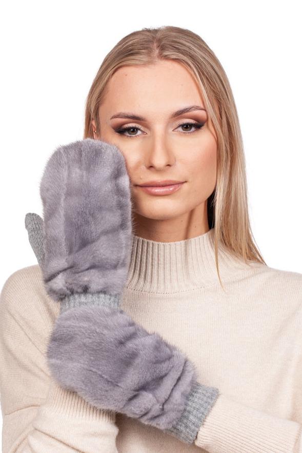 A woman with long blonde hair is wearing a cream turtleneck sweater and holding a Sapphire Mink Fur Flip Top Mitten by FurbySD up to her face, smiling softly against the plain white background.