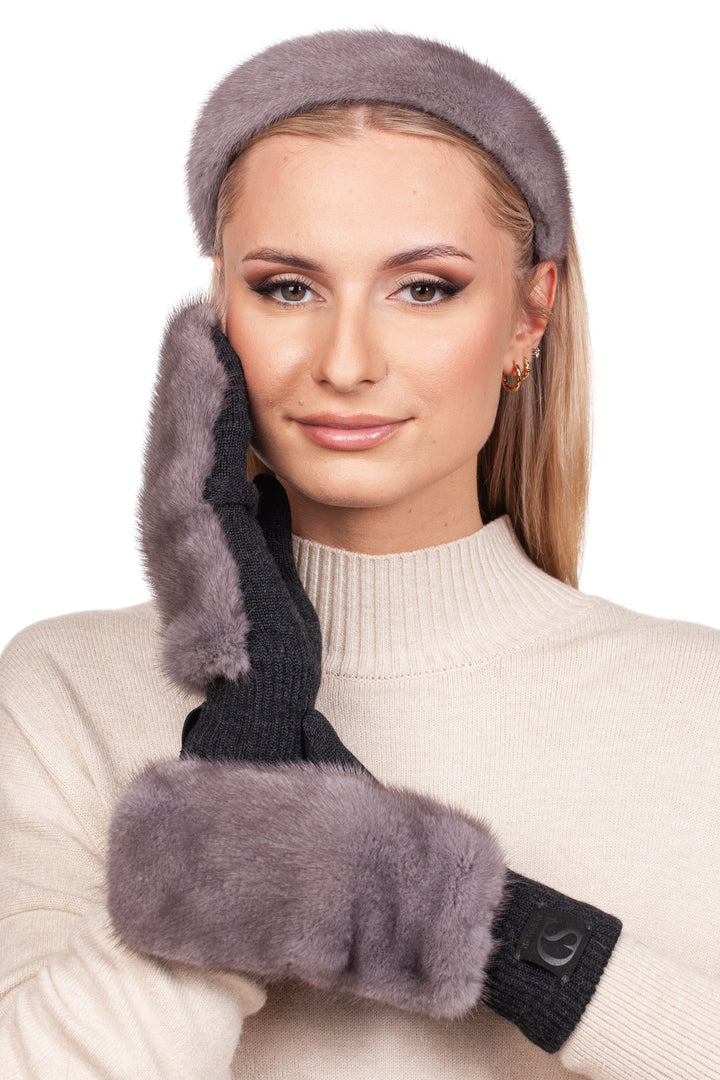 Donned in a cream sweater, an individual gracefully touches their face with one hand clad in luxurious gray fur mittens. They wear a matching Silverblue Mink Fur Headband by FurbySD, posing elegantly against the white backdrop.