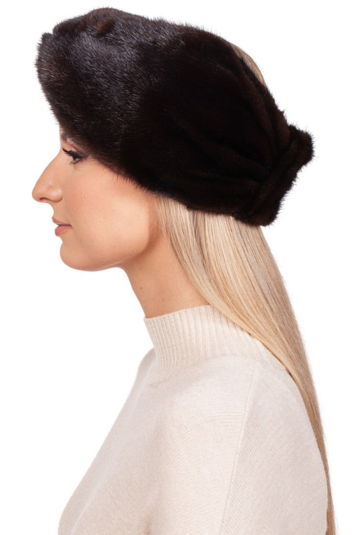 The individual with long blonde hair is sporting a genuine mink fur hat and a beige turtleneck sweater. The FurbySD Dark Brown Mink Fur Headband adds an elegant touch as they face to the left against a plain white background.