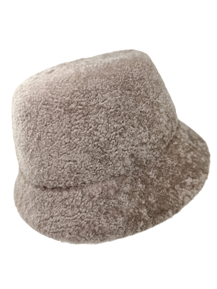 The Beige Lambskin Fur Hat With Brim by FurbySD, showcased against a white backdrop, radiates the allure of a high-end winter accessory. Its plush and warm texture, resembling beige lambskin fur, makes it perfect for chilly weather.