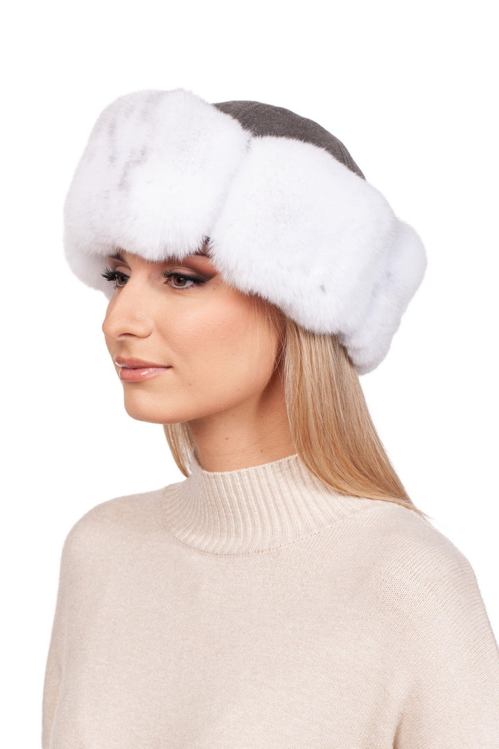 A woman with long blonde hair is wearing a chic White Chinchilla Fur Roller Hat by FurbySD and a beige turtleneck sweater. She is looking to the side against a plain white background.