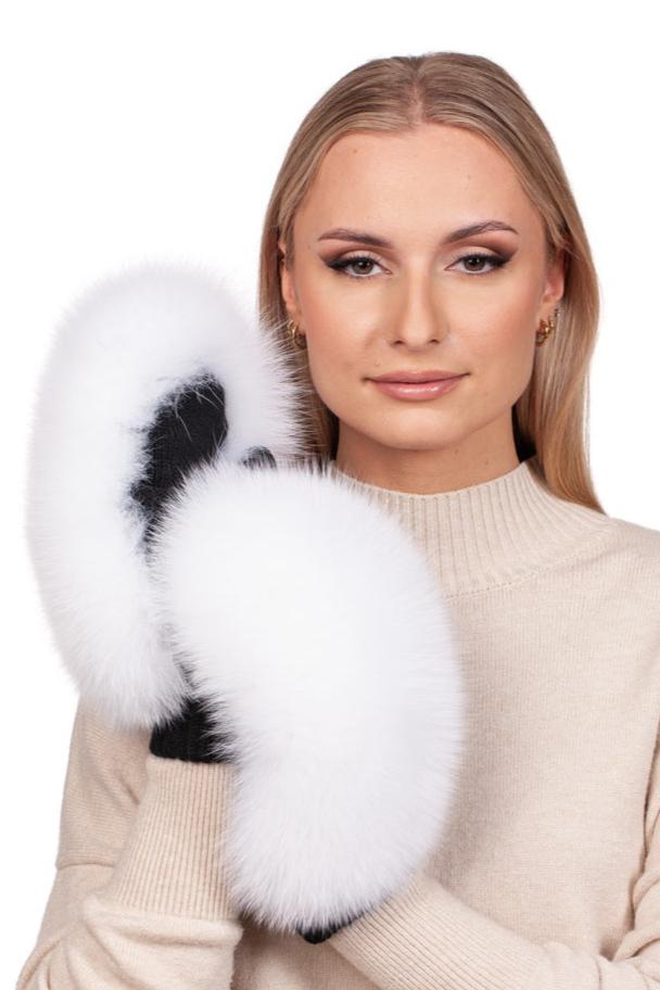 A person with long blonde hair is wearing a cream-colored sweater made of Merino wool and holding FurbySD's White Fox Fur Flip Top Mittens. The background is plain white.