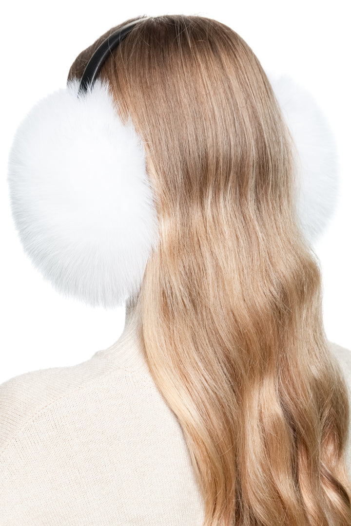 Close-up of soft white fox fur earmuffs with leather band, elegant winter ear warmer accessory.