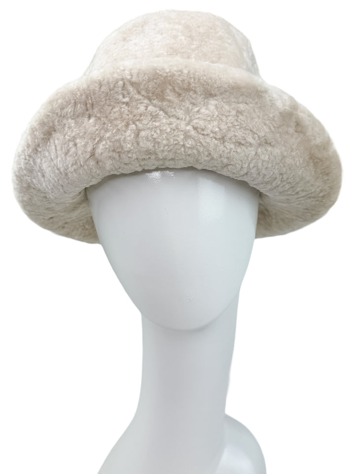 Displayed on a white mannequin head, the Pearl White Astrakhan Fur Bucket Hat from FurbySD features a cream-colored faux fur texture reminiscent of Astrakhan.