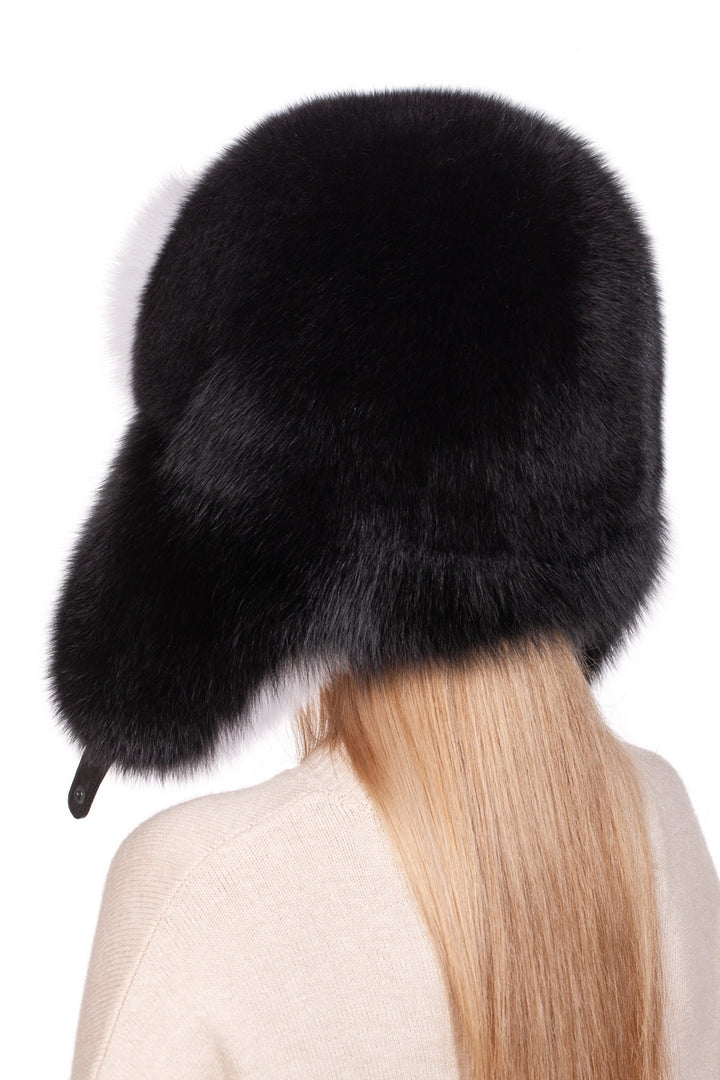 A person with long, light brown hair wears a large, fluffy Fox Fur Ushanka Trapper Hat by FurbySD, turned to the side and obscuring their face. This winter essential complements their beige sweater against a plain white background.