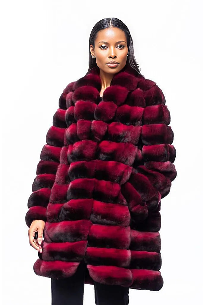 A model wearing the opulent FurbySD Red Chinchilla Fur Coat poses against a white background. The sophisticated striped pattern enhances the depth of the garment, while the individual stands poised, one hand slightly raised.