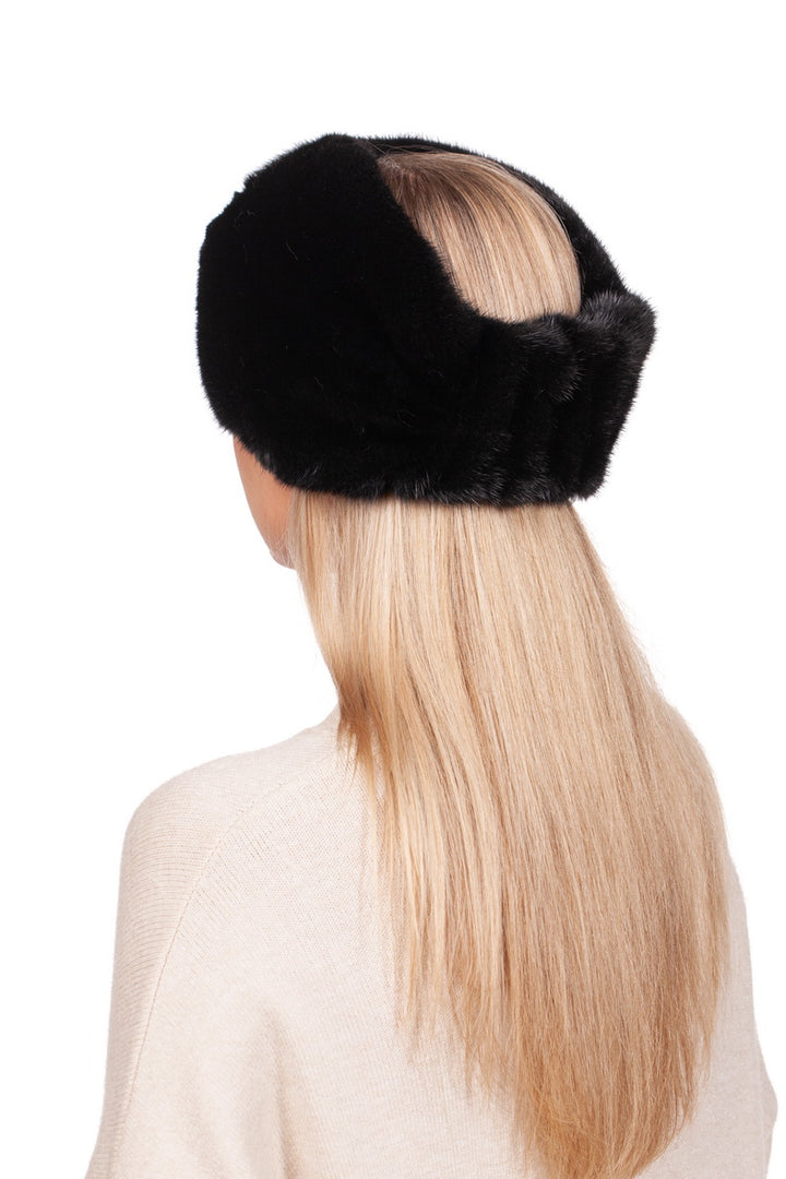 A person with long, blonde hair is seen from behind, adorned in a FurbySD Black Mink Fur Headband. They are wearing a light-colored sweater featuring a luxurious cashmere lining, set against a serene white background.