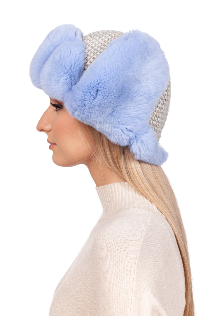 The side profile features a person wearing the Blue Chinchilla Fur Ushanka Hat by FurbySD, crafted in light gray knit and embellished with fluffy blue chinchilla fur accents. The ensemble is completed with their long blonde hair strikingly matching an ivory sweater against a plain white background.