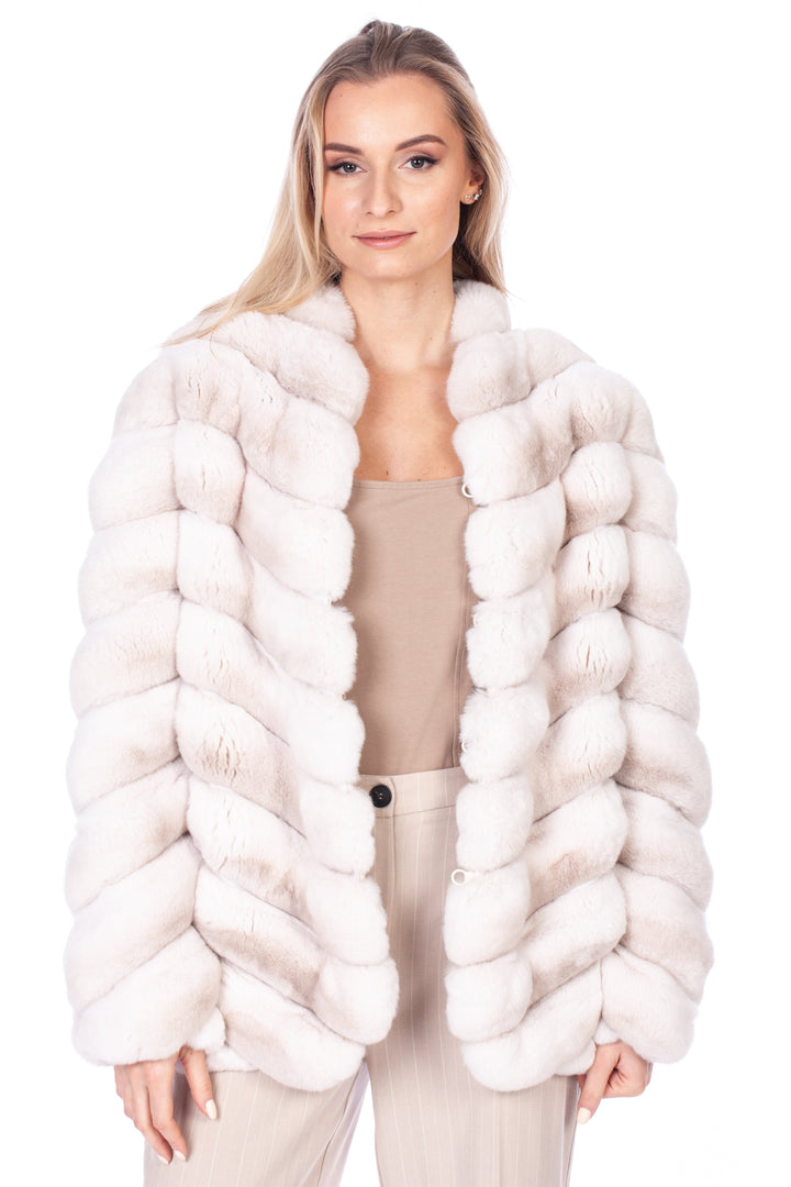 A person with long blonde hair models a luxurious Cream Chinchilla Fur Coat by FurbySD over a beige top and light-colored pants, set against a pristine white background.