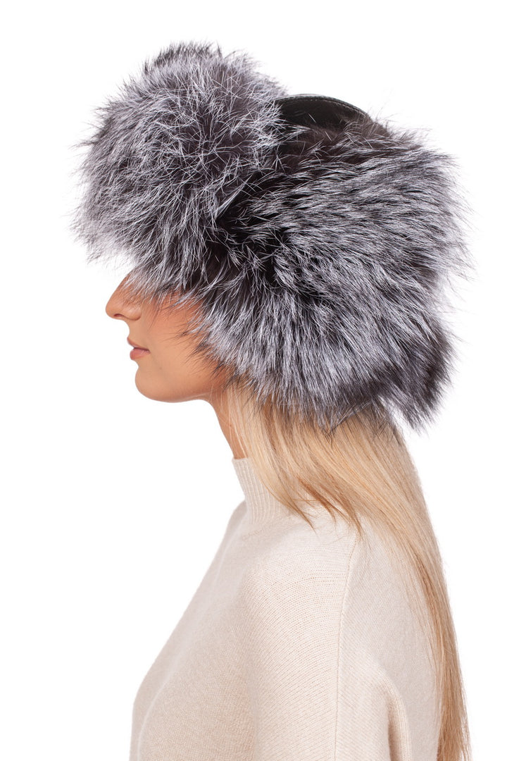 A person with long blonde hair is wearing a luxurious Silver Fox Fur Ushanka Trapper Hat by FurbySD, its fluffy gray warmth enveloping their ears. Against the plain white background, they pair this winter luxury with a cozy beige sweater, captured elegantly from the side.