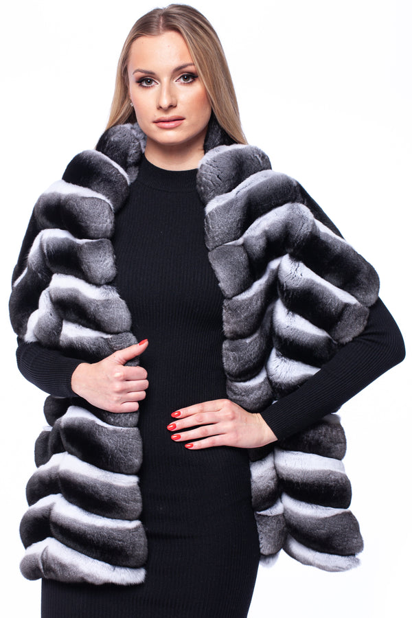 Woman wearing a black dress with a natural chinchilla fur stole on a white background.