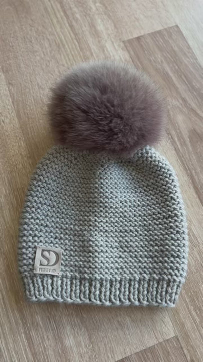 luxurious handknitted merino wool beanie in greyish beige with light beige fox fur pom pom.