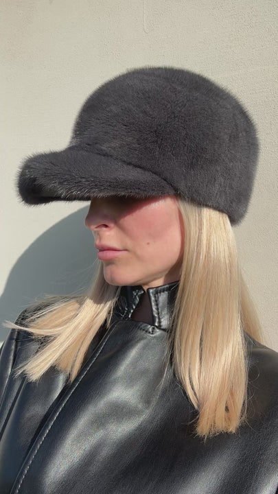 Handmade dark grey mink fur baseball cap with structured brim, unisex winter trucker hat shown at side angle on model, adjustable one-size design.