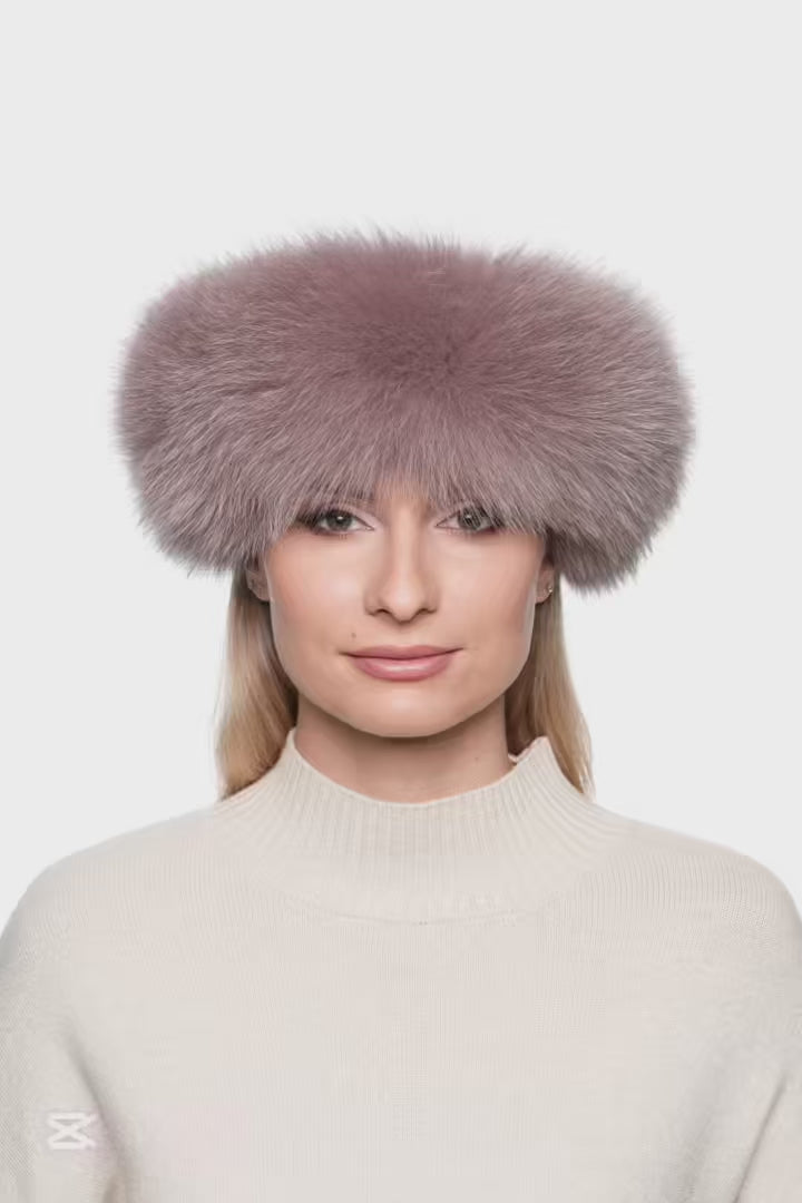 Women’s dusty pink fox fur headband, soft and voluminous real fur ear band worn across forehead, stylish luxury winter accessory.