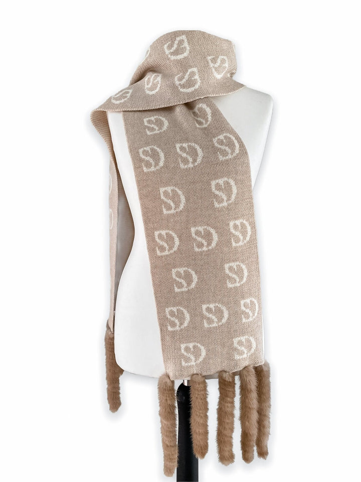 A beige wool scarf with white "D" patterns, crafted by FurbySD and featuring mink fur fringes at the ends, is elegantly draped over a white mannequin. This luxurious and cozy accessory exudes an exquisite and high-end appeal.