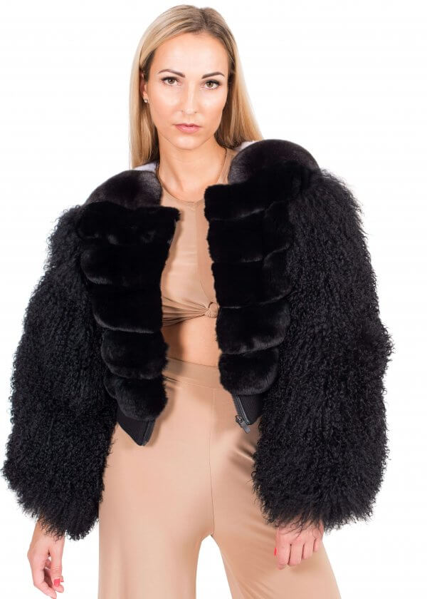 A woman with long blonde hair dons the stylish Chinchilla and Mongolian Lamb Fur Bomber Jacket by FurbySD, effortlessly pairing it with a beige ensemble as she stands against a pristine white backdrop.