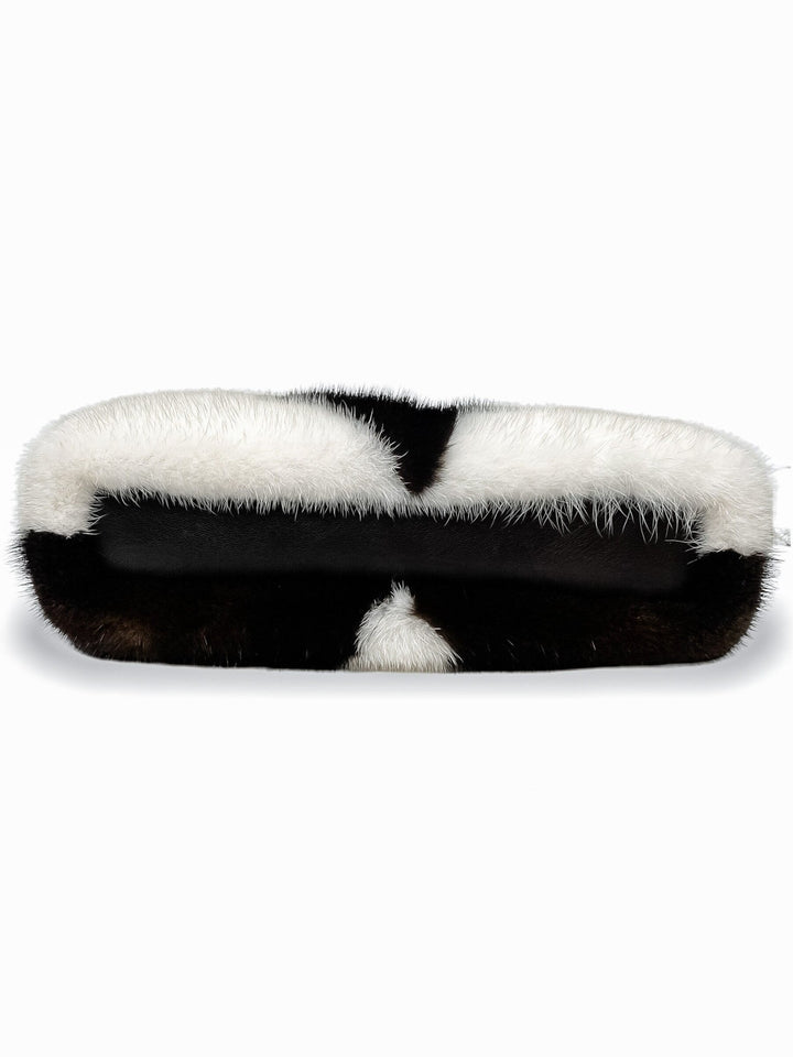 The Mink Fur Handbag by FurbySD is a stylish accessory handcrafted in Lithuania. This faux fur clutch showcases a sophisticated monochromatic black and white zigzag pattern, combining smooth and fluffy textures over its rounded shape. The sleek finish of the design is complemented by a detachable shoulder strap, enhancing its versatility.