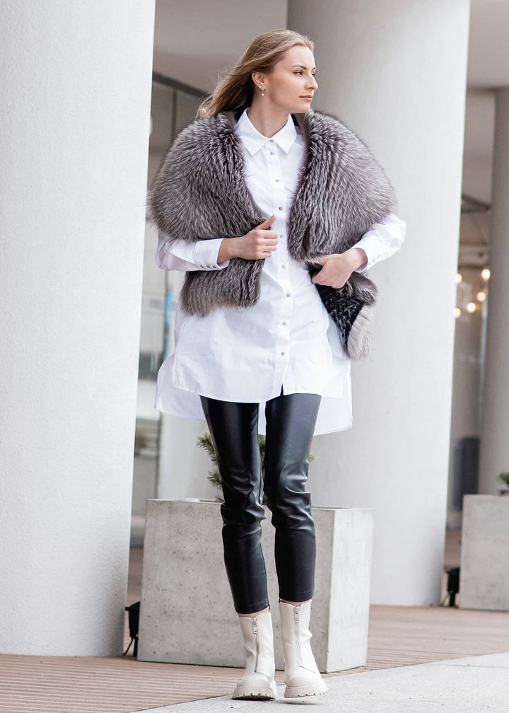 A person stands outdoors near a white column, wearing a white shirt dress, black leather pants, and white ankle boots. They have a FurbySD Silver Fox Fur Stole draped over their shoulders and are looking to the side with a slight smile.