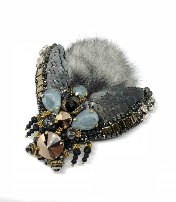 Introducing the Swarovski Brooch with Chinchilla Fur by FurbySD: a stunning decorative piece in the shape of a bee, adorned with sparkling black and brown sequins, beads, and elegant gold-tone accents. The wings are embellished with chinchilla fur detailing to enhance texture and contrast in this exquisite design.